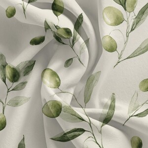 May include: Off-white fabric with a repeating watercolor pattern of olive branches. The design features green olives and leaves on slender stems, creating a natural, botanical theme. The fabric has soft folds and a subtle sheen.