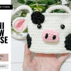 May include: A handmade white crochet mini cow purse with black spots, pink ears, and a pink nose. The purse has black bead eyes and a white handle. The text "CROCHET PATTERN" and "MINI COW PURSE" are visible.