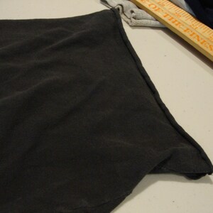 May include: Close-up of the black fabric edge of a garment, showing the stitching detail.