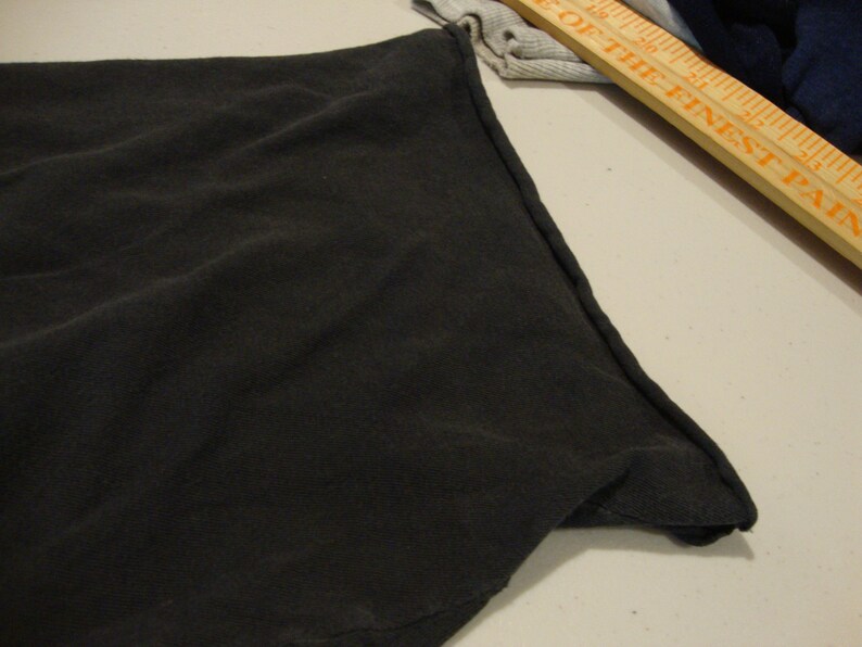 May include: Close-up of the black fabric edge of a garment, showing the stitching detail.