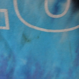 May include: A blue and white tie-dye fabric with a white outline of a circle and a square.