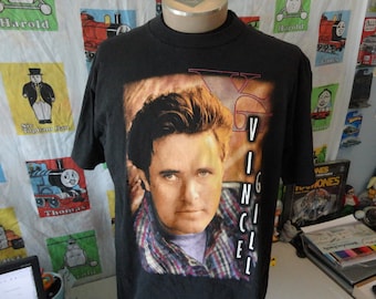 May include: Black t-shirt with a photo of singer Vince Neil from the band Motley Crue. The shirt has the word "Vince" printed vertically down the right side of the image.
