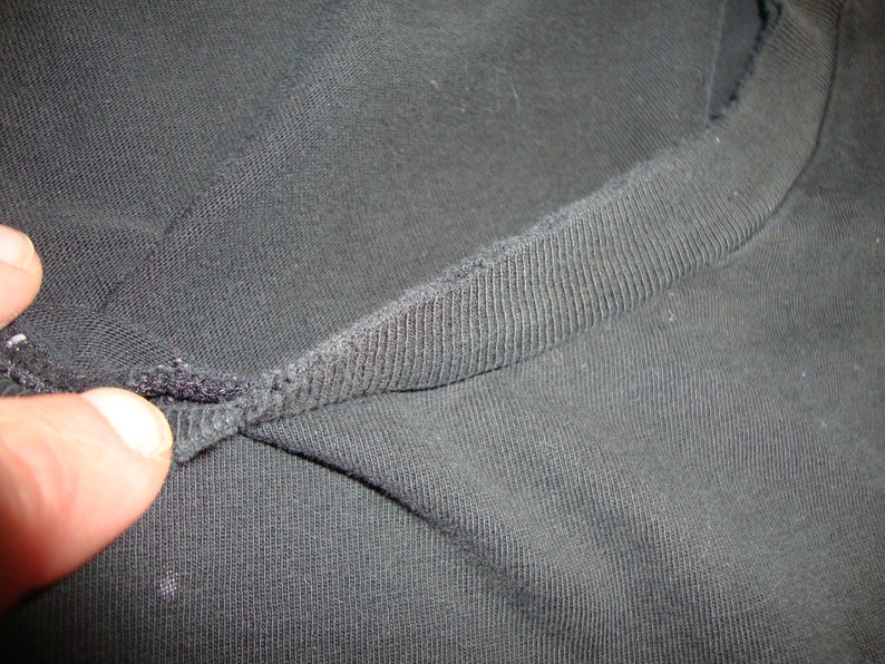 Puede incluir: Primer plano del cuello de una camiseta negra que muestra la tela de punto de canal&eacute;.