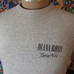 Peut inclure: T-shirt gris avec du texte noir qui dit "Diana Ross Eaten Alive".