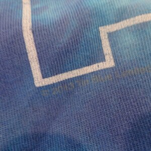 May include: Close-up of a blue tie-dye t-shirt with white text that reads "&copy; 2017  " followed by a logo.
