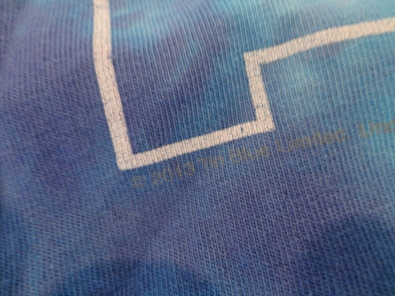 May include: Close-up of a blue tie-dye t-shirt with white text that reads "&copy; 2017  " followed by a logo.