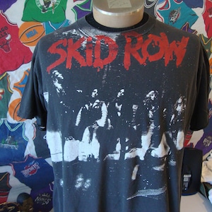 May include: Black t-shirt with a white print of a band called "SKID ROW". The band members are pictured in the print.