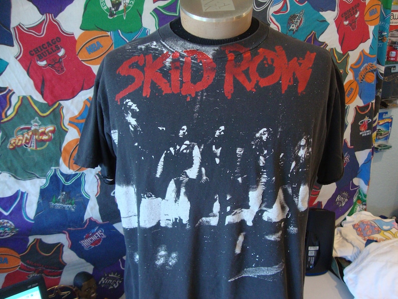May include: Black t-shirt with a white print of a band called "SKID ROW". The band members are pictured in the print.