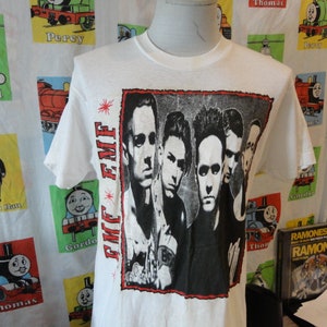 May include: White t-shirt with a black and white graphic print of a band called "E.M.F."