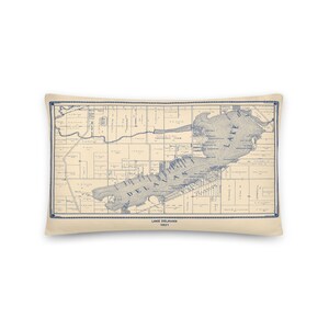 May include: A vintage map of Lake Delavan, Wisconsin, printed in blue ink on a cream background. The map shows the lake and surrounding area, including roads, buildings, and landmarks. The map is dated 1921.