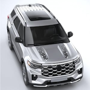 Könnte beinhalten: Silberner SUV mit schwarzem Panorama-Schiebedach. Das Fahrzeug hat einen markanten Frontgrill und rautenförmige Akzente auf der Motorhaube. Das Auto wird von oben gezeigt, was sein schlankes Design und seine modernen Merkmale hervorhebt.