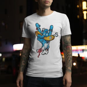 May include: White t-shirt with a graphic of a blue hand holding a yellow skateboard. The hand is making a rock and roll hand gesture. The skateboard has red and white stripes.