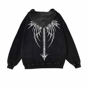 May include: Black hooded sweatshirt with a white graphic on the back. The design depicts a stylized spine and wing-like elements. The sweatshirt has long sleeves and a drawstring hood.