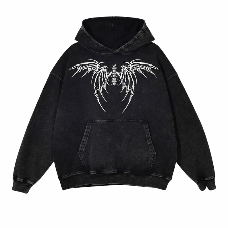 May include: Black hoodie with a white graphic design. The design is a stylized wing or insect-like pattern. The hoodie has a hood and a front pocket. It is made of a soft, comfortable material.