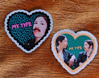 May include: Two heart-shaped stickers with scalloped edges. The left sticker features a person with a mustache against a teal leopard print background with the text MY TYPE in pink. The right sticker shows two people with the text MY TYPE in yellow.