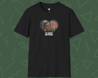 May include: Black t-shirt featuring a heart-shaped graphic with a portrait of a man and the text "MY MUSIC BOYFRIEND" in white. The shirt has short sleeves and a crew neck.