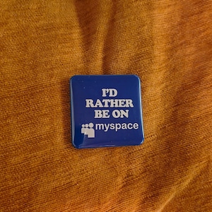 May include: A square, blue button with the text "I'D RATHER BE ON myspace" in white. The button is set against a textured, orange-brown background.