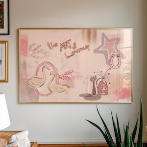 May include: A framed artwork with a soft pink background features the text "the ART of Loving". The artwork includes illustrations of swans, a star, a horseshoe, and vases. The frame is gold.