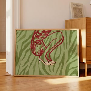 May include: A rectangular framed wall art print featuring a stylized illustration of a person in a crouched position. The figure is outlined in red against a muted olive green zebra-striped background, wearing polka-dot high-heeled shoes.
