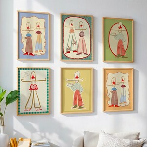 May include: Six framed art prints with whimsical illustrations of figures wearing hats and outfits in various colors. The artwork features a minimalist style with red star accents and a playful aesthetic, displayed on a white wall.