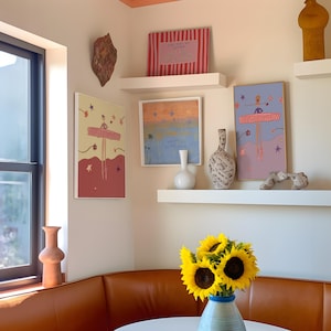 May include: An interior shot featuring a corner with artwork, shelves, and a leather bench. The artwork includes framed prints with abstract and figurative designs. A vase of sunflowers sits on a table. Decorative vases and a window are also visible.