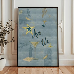 May include: A framed wall art print featuring a dusty blue background with gold and dark blue star illustrations, a martini glass with two olives, and the text Are We written in a dark blue script font, accented by subtle botanical line drawings.