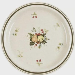 May include: Round, off-white ceramic plate with a fruit and floral design. The center features a still life of a pear, apple, and berries. The rim has two dark green bands. Small floral and berry accents are scattered around the plate.