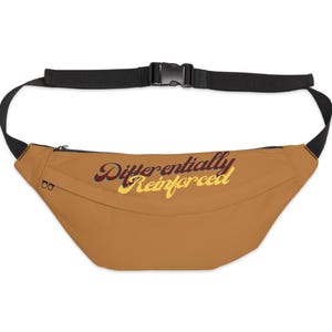 May include: A brown fanny pack with a black adjustable strap and buckle closure. The bag features the text "Differentially Reinforced" in a retro font across the front. The fanny pack has a zippered pocket.