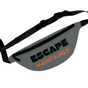 May include: Gray fanny pack with black trim and adjustable strap. The text "ESCAPE MAINTAINED" is printed on the front in black and orange. The fanny pack has a black zipper and buckle.