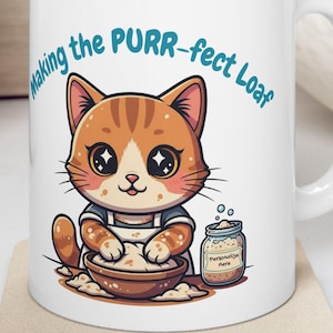 Puede incluir: Taza de cerámica blanca con un gato de dibujos animados horneando, con el texto "Making the PURR-fect Loaf". El gato es naranja y blanco, lleva un delantal y tiene ojos grandes. Un tarro de ingredientes está al lado del gato.