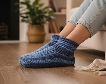 May include: Cozy blue knitted slipper socks with a striped pattern. The socks are a mix of light and dark blue hues, perfect for indoor wear. The socks are on a wooden floor.