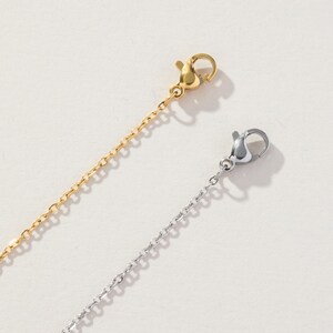 May include: Two delicate metal chains, one in a polished gold tone and one in a bright silver tone. Each chain features a small, functional lobster claw clasp at the end, designed for securing jewelry pieces with a simple and reliable mechanism.