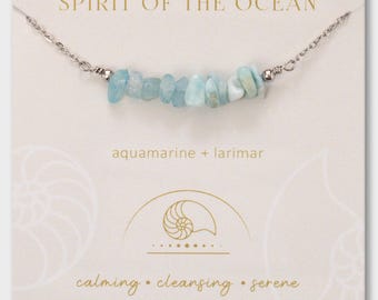 Può includere: Una collana con catena color argento e una fila centrale di pietre di acquamarina e larimar azzurre burattate. Il cartoncino di presentazione riporta la scritta SPIRIT OF THE OCEAN, aquamarine + larimar, e calming • cleansing • serene.