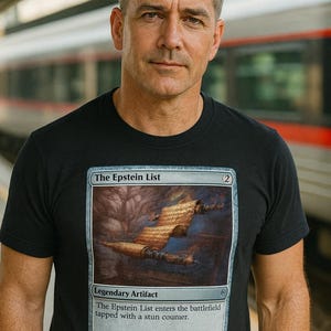 May include: Black t-shirt with a Magic: The Gathering card design. The card is titled "The Epstein List" and features a stylized image with text that reads "Legendary Artifact" and flavor text. The shirt is worn by a person.
