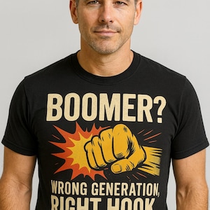 May include: Black t-shirt featuring the text "BOOMER?" and a graphic of a fist. Underneath, it reads "WRONG GENERATION, RIGHT HOOK". The shirt is worn by a person.