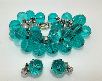 May include: A turquoise blue beaded bracelet and matching earrings. The bracelet is made of faceted glass beads and silver tone metal. The earrings are clip-on style.