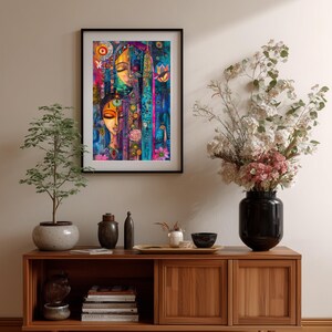 May include: A framed art print with an abstract design and two faces, in a vibrant palette of blues, pinks, and yellows. The print hangs above a wooden cabinet with decorative items and a vase of flowers. The cabinet is made of wood.