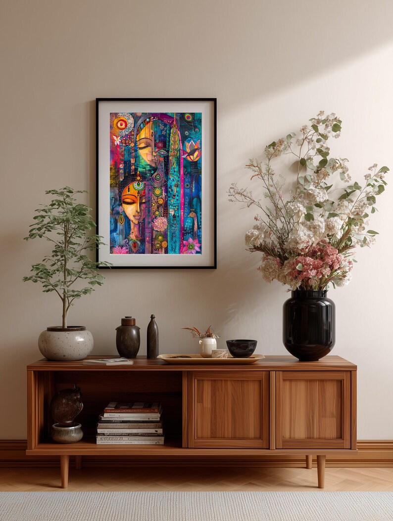 May include: A framed art print with an abstract design and two faces, in a vibrant palette of blues, pinks, and yellows. The print hangs above a wooden cabinet with decorative items and a vase of flowers. The cabinet is made of wood.