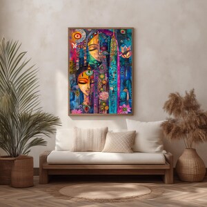 May include: A framed abstract painting with two stylized faces. The artwork uses blues, pinks, and yellows, with intricate patterns and floral motifs. The painting is displayed above a wooden sofa with white cushions. The painting is in a wooden frame.