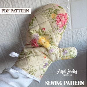 May include: A quilted oven mitt with a floral pattern featuring pink, yellow, and purple flowers on a cream background. The mitt has a white loop for hanging and the text "PDF PATTERN" and "SEWING PATTERN" are visible.