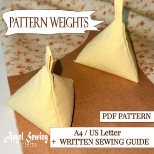 May include: Two pale yellow, triangular pattern weights with a loop handle are shown. The text "PATTERN WEIGHTS" is at the top. The text "PDF PATTERN" and "A4/US Letter + WRITTEN SEWING GUIDE" are at the bottom. The brand name "Angel Sewing patterns" is also visible.