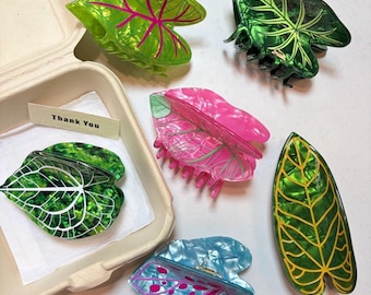 May include: Six hair claw clips shaped like leaves in various colors including translucent green with pink veins, dark green with light veins, pink with green veins, blue with pink spots, and green with yellow veins, plus a Thank You note.