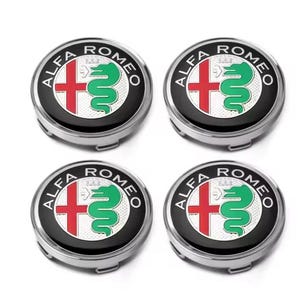 May include: Four Alfa Romeo wheel center caps. Each cap features the Alfa Romeo logo: a red cross and a green serpent on a white background, surrounded by a black ring with the brand name in white letters. The caps have a silver finish.