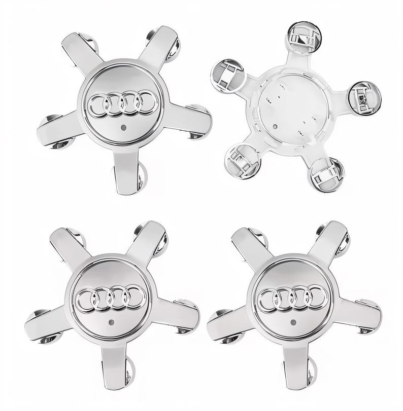 Puede incluir: Cuatro tapacubos plateados de Audi. Cada tapacubos tiene un dise&ntilde;o de estrella de cinco puntas con el logotipo de Audi en el centro. Se muestra un tapacubos desde la parte trasera, revelando los clips de montaje.