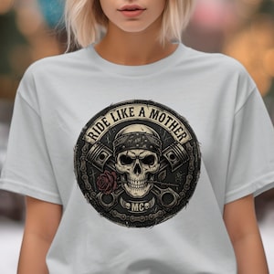May include: Light gray t-shirt featuring a circular graphic with a skull wearing a bandana, crossed pistons, and a rose. The text "RIDE LIKE A MOTHER" is arched above the skull, with "MC" below.