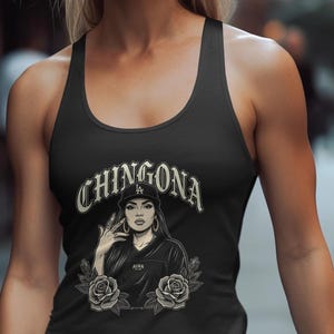 May include: Black tank top featuring a graphic of a woman wearing a cap with the text "CHINGONA" above her. The graphic includes roses and the word "AURA".