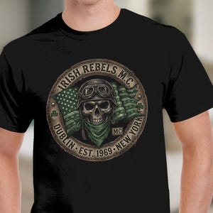 May include: Black t-shirt featuring a circular graphic with a skull wearing goggles and a bandana. The graphic includes a green and white flag, the text "IRISH REBELS M.C. DUBLIN EST. 1969 NEW YORK", and the letters "MC".