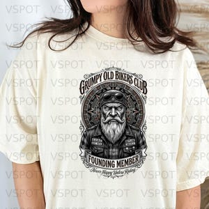 May include: A cream-coloured t-shirt with a graphic of an elderly biker wearing sunglasses and a long white beard. The design includes the text "Grumpy Old Bikers Club" and "Founding Member".