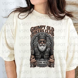 May include: Cream-colored t-shirt featuring a graphic of an older biker with a long white beard, wearing a vest and a bandana. The text "GRUMPY OLD BIKERS CLUB" is above the biker, and "FOUNDING MEMBER" is below.