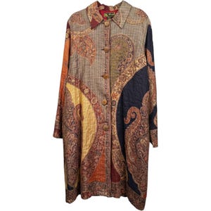 Puede incluir: Un abrigo de manga larga con botones frontales, textura acolchada y un estampado de cachemira multicolor en tonos azul marino, amarillo mostaza, naranja quemado y beige. La prenda cuenta con un cuello estándar y una etiqueta de marca visible.